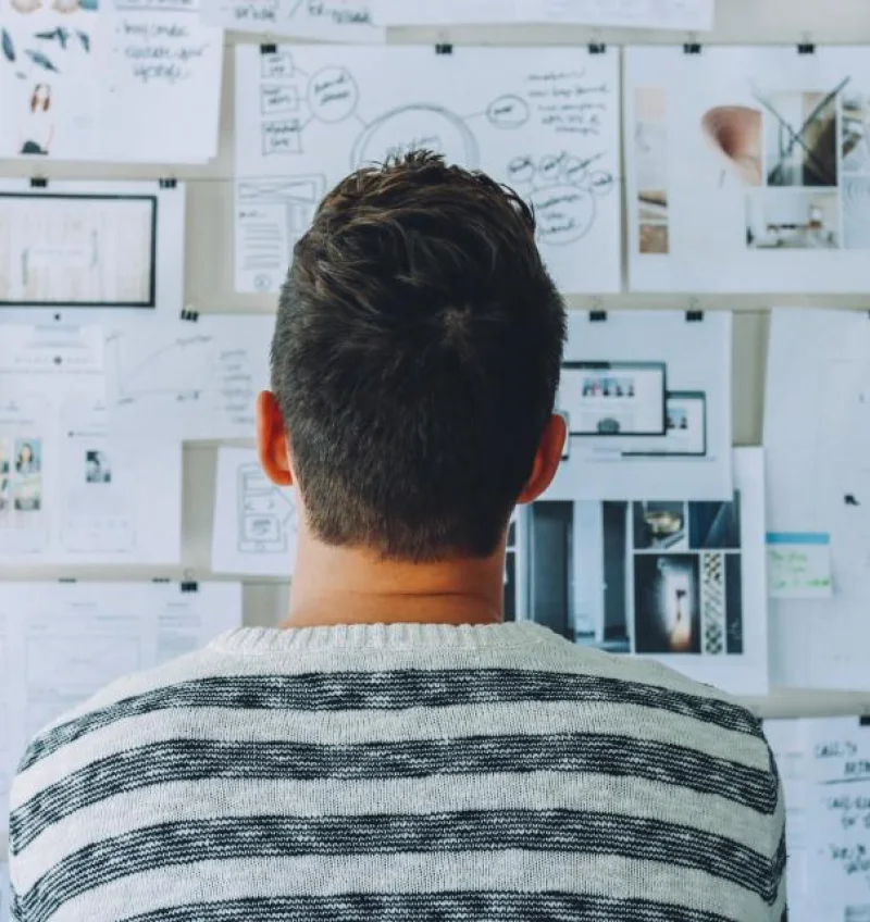 Art director reviewing printed layouts pinned to a studio wall
